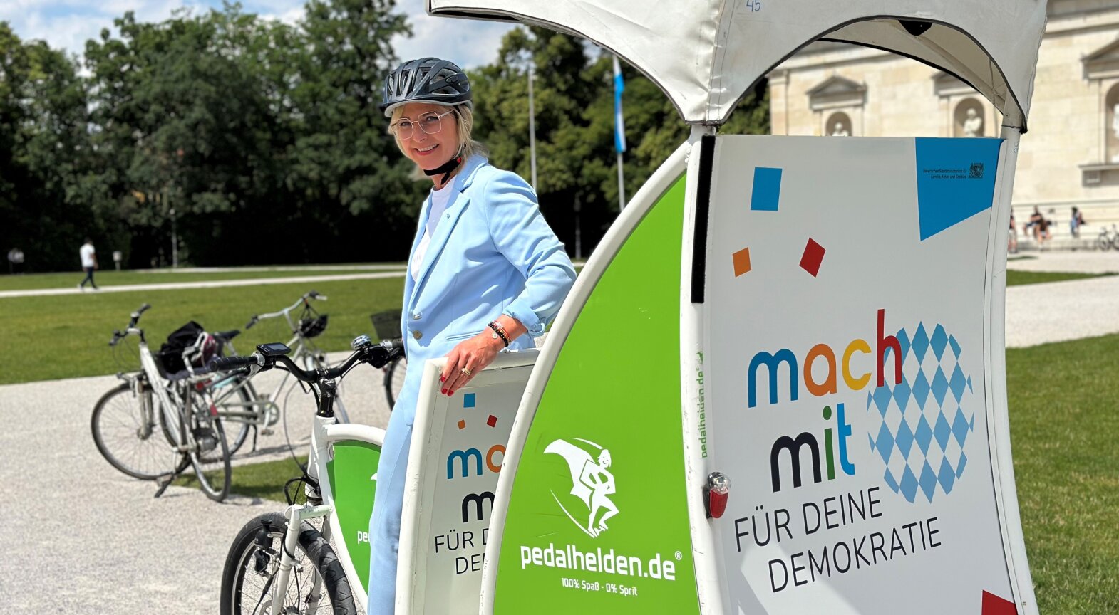 Das Foto zeigt Sozialministerin Ulrike Scharf bei ihrer Rikscha-Fahrt durch München am Etappenziel Königsplatz.